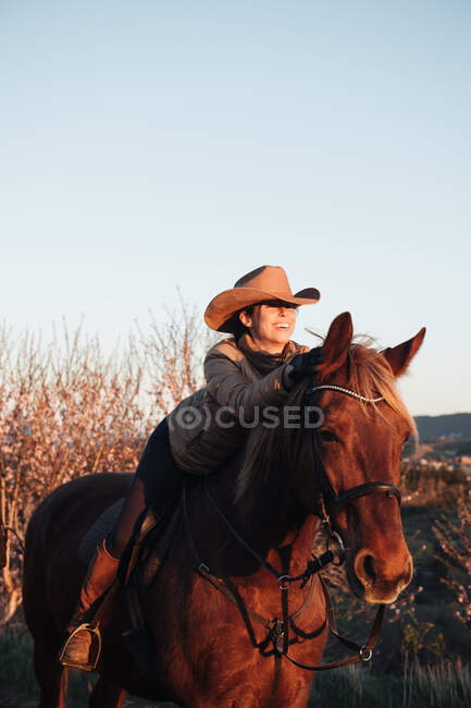 Femme cheval équitation contre le coucher du soleil ciel sur ranch — Photo de stock