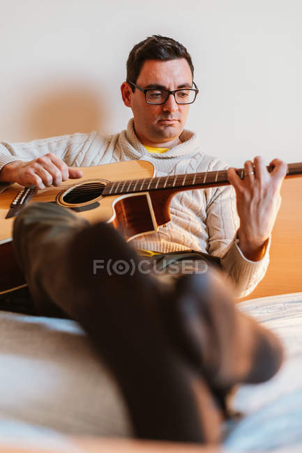 Homem tocando guitarra na cama em casa — Fotografia de Stock