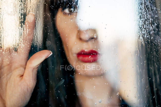 Closeup of sensual female with red lips touching transparent glass — Stock Photo