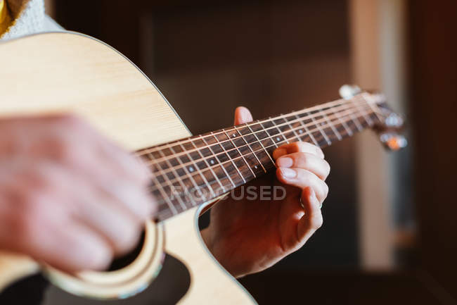 Manos del hombre tocando la guitarra sobre fondo borroso - foto de stock
