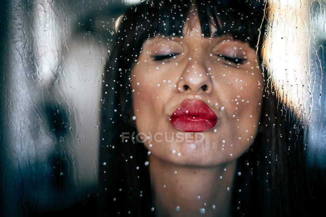 Attraktive Frau mit roten Lippen küsst sauberes transparentes Glas leidenschaftlich — Stockfoto