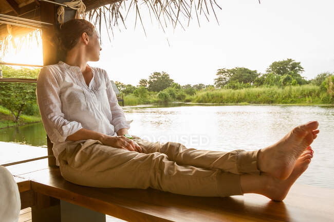 Босонога жінка дивиться на спокійне озеро — стокове фото