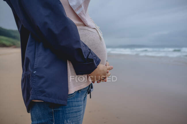 Donna incinta in piedi sulla spiaggia — Foto stock