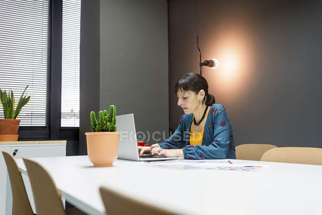 Businesswoman working on laptop while sitting at desk in office — Stock Photo