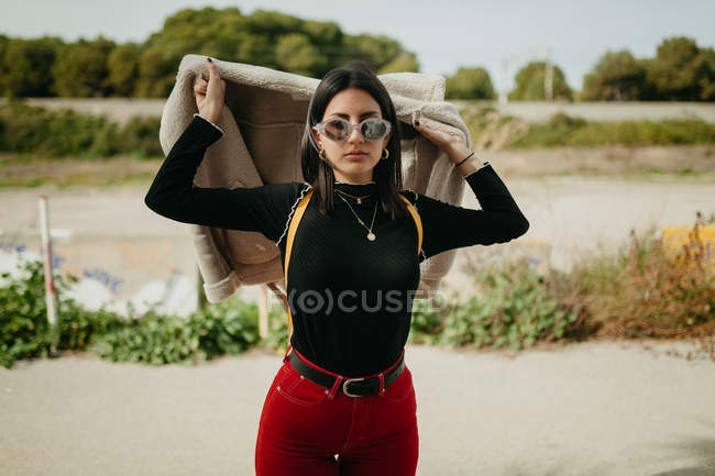 Porträt einer jungen Frau im trendigen Outfit mit Jacke vor verschwommenem Küstenhintergrund — Stockfoto