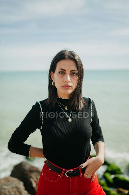 Чувственная женщина смотрит в камеру, стоя на солнечном пляже — стоковое фото