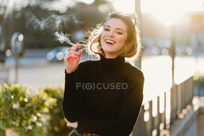 Hübsche Frau raucht Zigarette auf sonniger Straße — Stockfoto