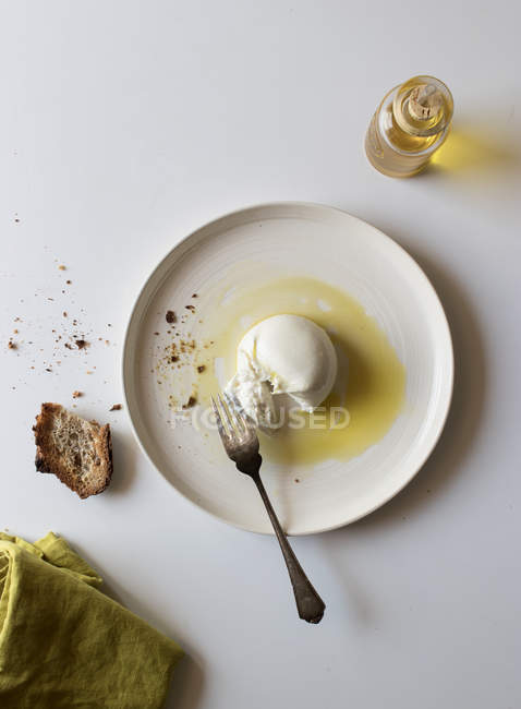 Plate with delicious fresh burrata on white tabletop near piece of bread and oil with salt — Stock Photo