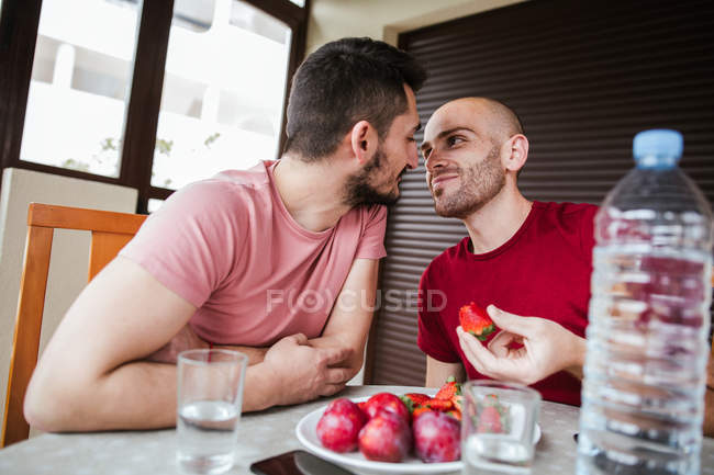 Gay casal comer morangos e olhando para o outros — Fotografia de Stock