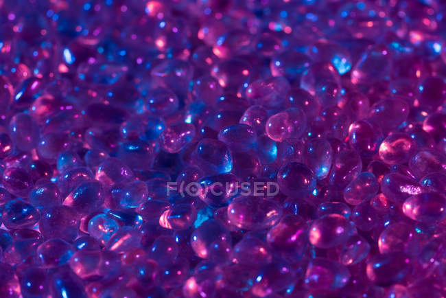 De cima pequenas pedras de opala welo cruas colocadas em pilha sob luz azul e rosa — Fotografia de Stock