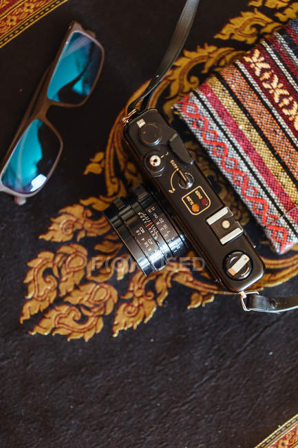 Вінтажна камера на декоративному столі з блокнотом і сонцезахисними окулярами — стокове фото