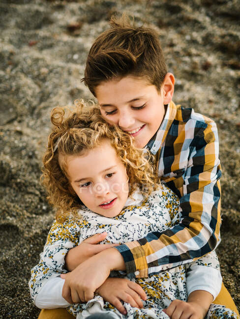 Joyeux et mignon garçon et fille souriant et se serrant dans ses bras à la plage — Photo de stock