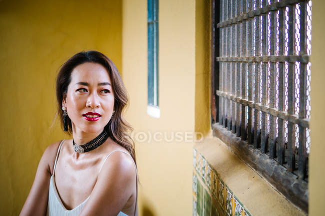 Young trendy chinese woman posing near building wall — Stock Photo