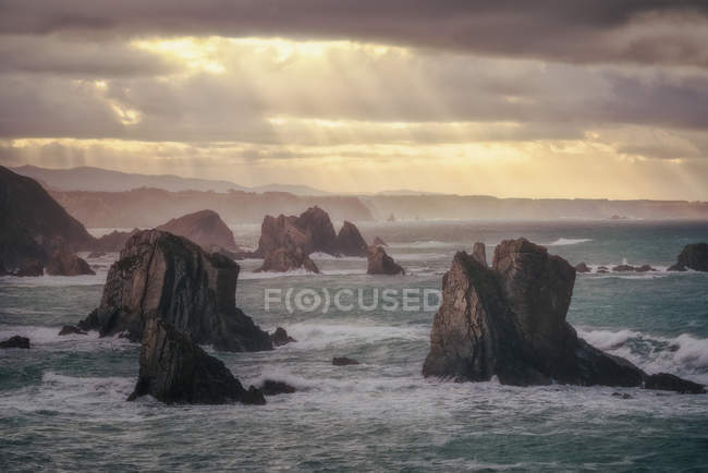 Живописный вид на скалу на спокойном гладком берегу моря на фоне серого неба — стоковое фото