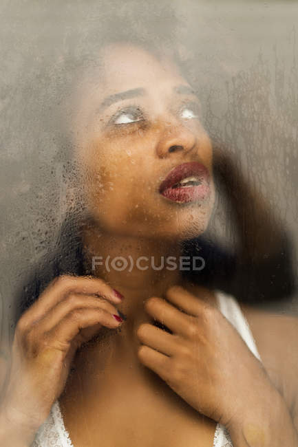 Portrait de femme noire sensuelle derrière la fenêtre mouillée — Photo de stock