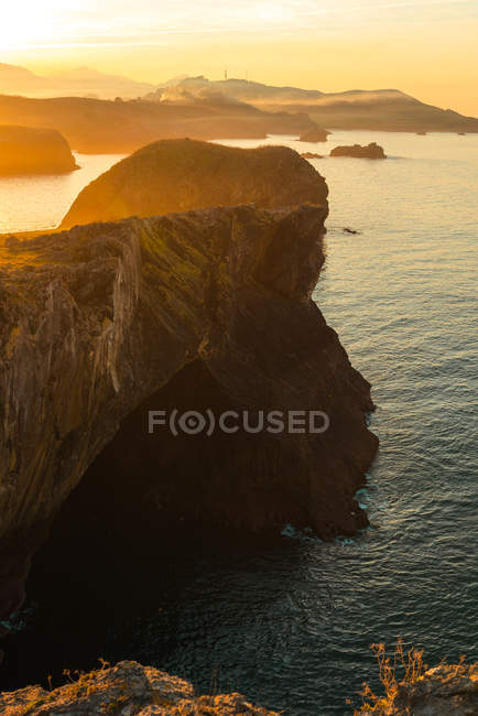 Vista panoramica di enormi scogliere rocciose sopra l'acqua increspata contro il cielo del tramonto, Asturie, Spagna — Foto stock