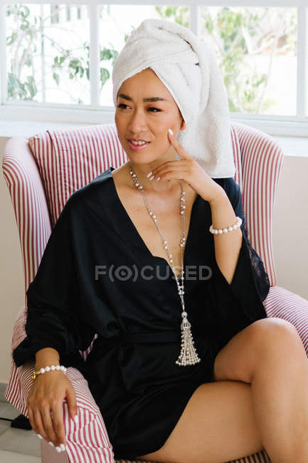 Elegant chinese wealthy woman with towel on head sitting in armchair — Stock Photo