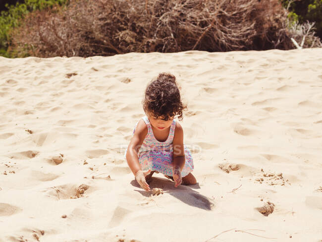 Linda niña jugando con arena en la playa - foto de stock