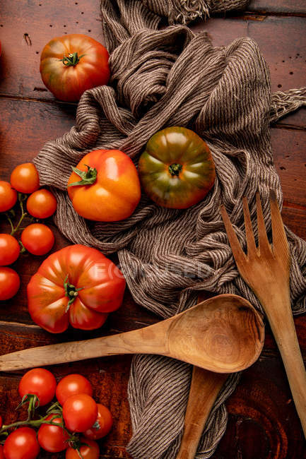 Pomodori freschi assortiti e tessuto su piano in legno in cucina — Foto stock