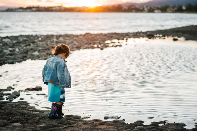 Unrecognizable girl standing by the seashore at sunset — Stock Photo