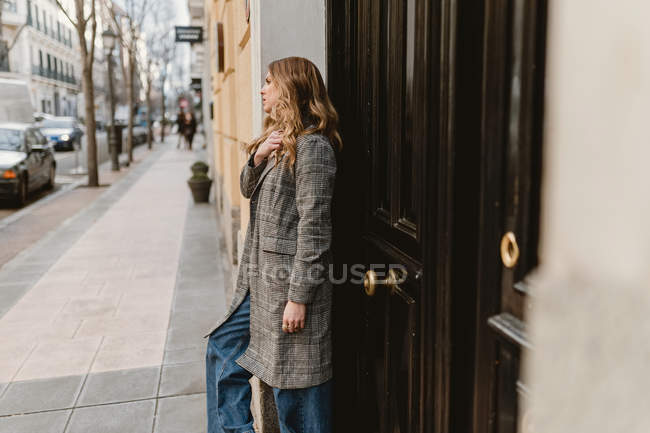 Stylish young thoughtful woman leaning on wall on street — Stock Photo