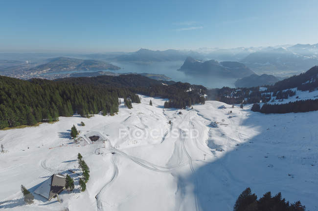 Vista panorámica de la ladera nevada con complejo en el fondo de las montañas en la bruma y la luz del sol, Suiza - foto de stock
