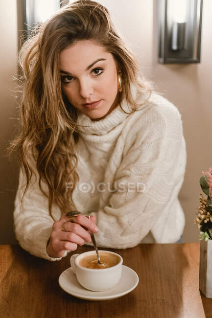 Елегантна жінка змішує каву в кафе — стокове фото