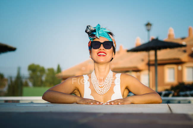 Young rich chinese woman sunbathing at swimming pool at luxurious resort — Stock Photo