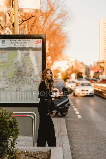 Стильная женщина стоит рядом со станцией метро в городе — стоковое фото