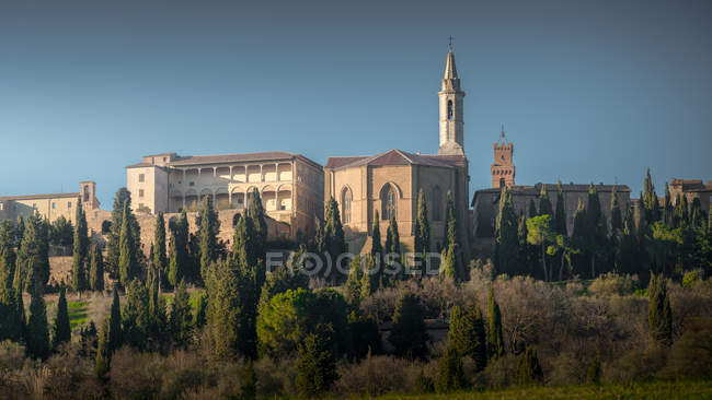 Blick auf die alte Kathedrale zwischen grünen Zypressen in der Landschaft der Toskana, Italien — Stockfoto
