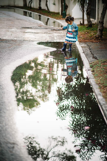 Small girl playing with puddle in street — Stock Photo