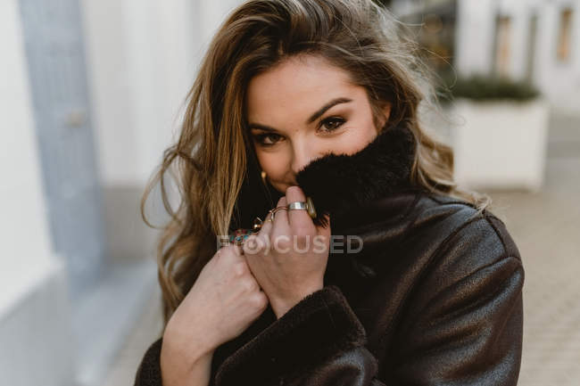 Cheerful attractive woman looking at camera on city street — Stock Photo