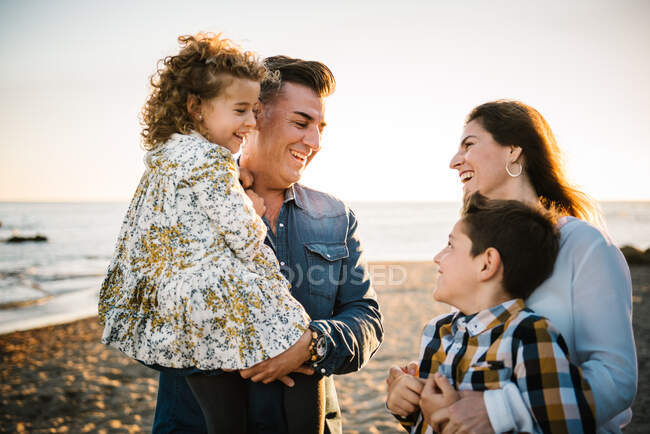 Homme d'âge moyen une femme avec des enfants au bord de la mer souriant et s'embrassant — Photo de stock