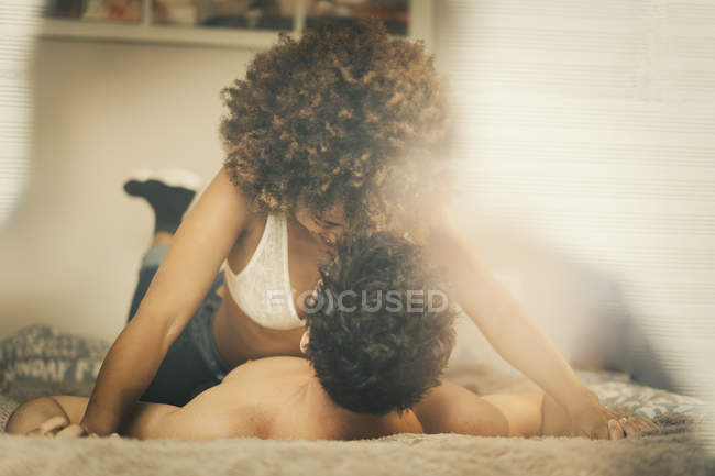 Jeune homme et femme sensuels couchés sur le lit et câlins dans une chambre confortable à la maison — Photo de stock