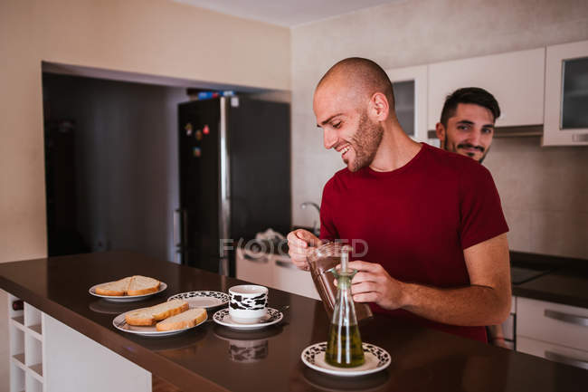 Feliz gay casal ter pequeno-almoço no cozinha juntos — Fotografia de Stock