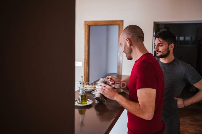 Happy gay couple having breakfast in kitchen together — Stock Photo