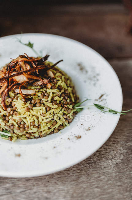 Prato de delicioso prato árabe tradicional Mujaddara em placa na mesa de madeira — Fotografia de Stock