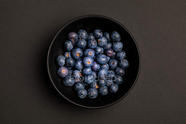Schüssel mit köstlichen reifen Blaubeeren auf schwarzem Hintergrund — Stockfoto