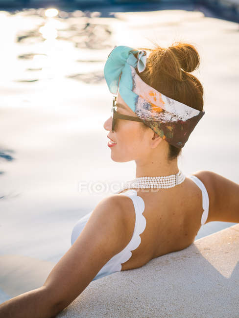 Young rich chinese woman relaxing swimming in a pool at a luxurious resort — Stock Photo