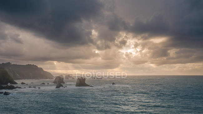 Pintoresca vista de espectacular bahía rodeada de majestuosos acantilados sobre fondo de cielo brillante con nubes lluviosas - foto de stock