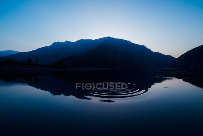 Picturesque view of water surface near amazing rock hills at sunset and blue sky — Stock Photo