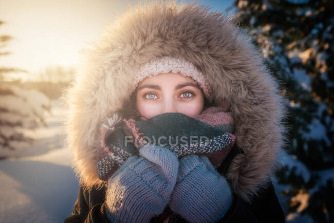 Young attractive female in warm clothing with fur joyful laughing beside covered snow conifer tree — Stock Photo