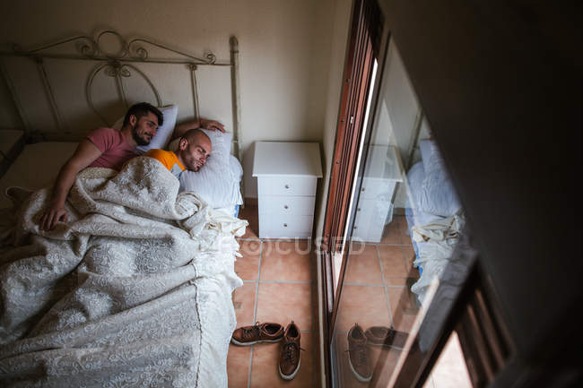 Обнимающая гей-пара, отдыхающая в постели утром — стоковое фото