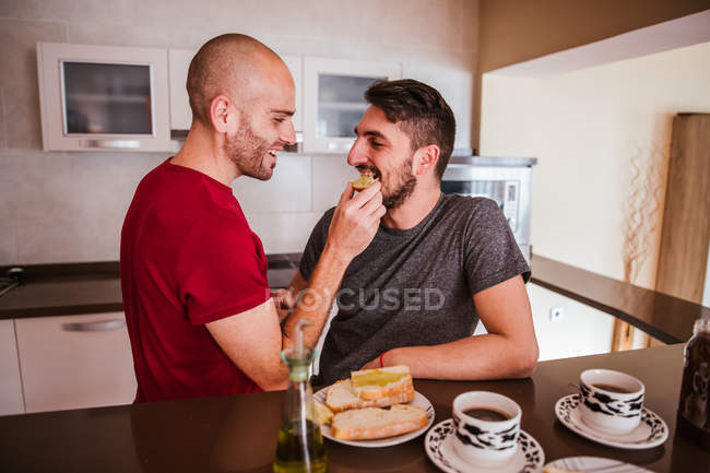 Feliz gay casal ter pequeno-almoço no cozinha — Fotografia de Stock