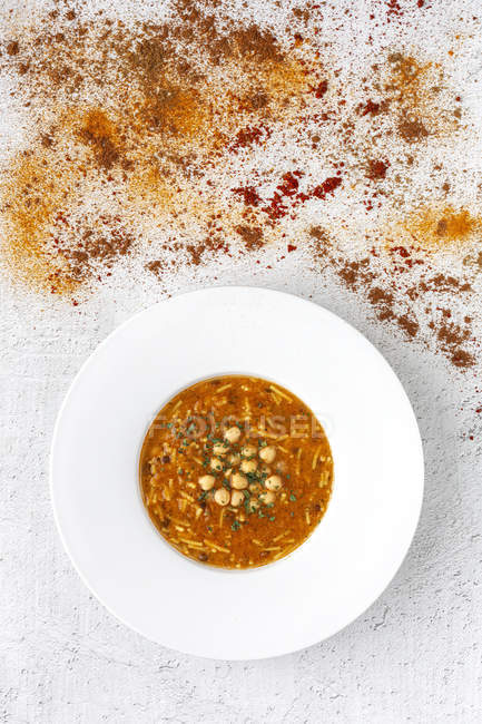 Traditional Harira soup for Ramadan in plate on white tabletop with scattered spices — Stock Photo