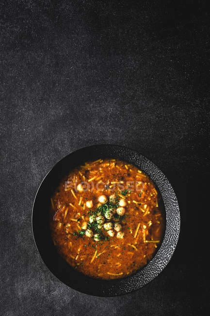 Traditional Harira soup for Ramadan in black bowl on dark tabletop — Stock Photo