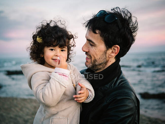 Cute scene of dad holding and hugging her little daughter at the beach in winter — Stock Photo