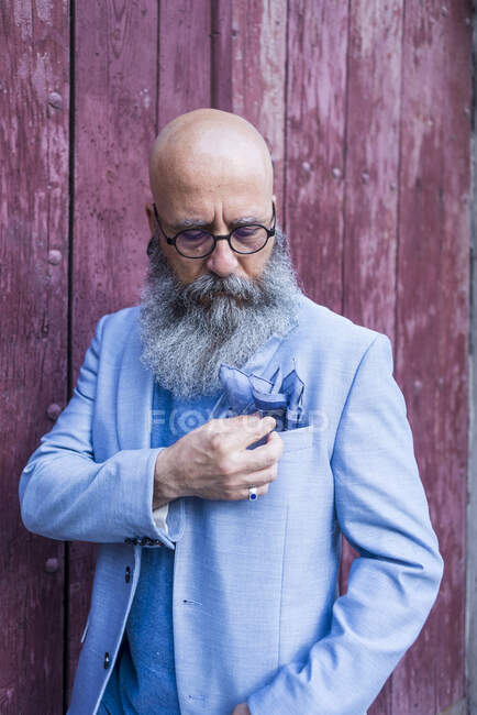 Maturo hipster barbuto alla moda in piedi contro una porta rossa vintage all'aperto — Foto stock