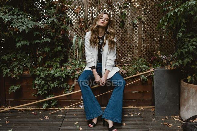 Жінка сидить на плантаторі в саду — стокове фото