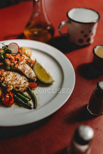 Grilled chicken breast and vegetables on white plate on red background — Stock Photo
